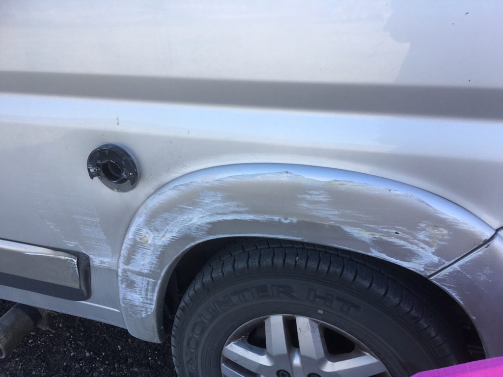 a badly scraped side of the van with a broken heater vent