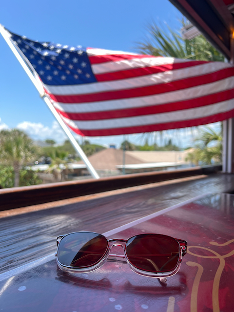 sunglasses in the foreground, an American flag in the background